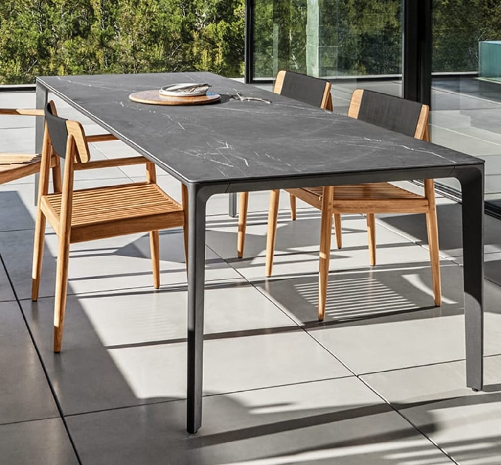 Metal finish luxury dining table with wooden finish dining chairs by Gloster